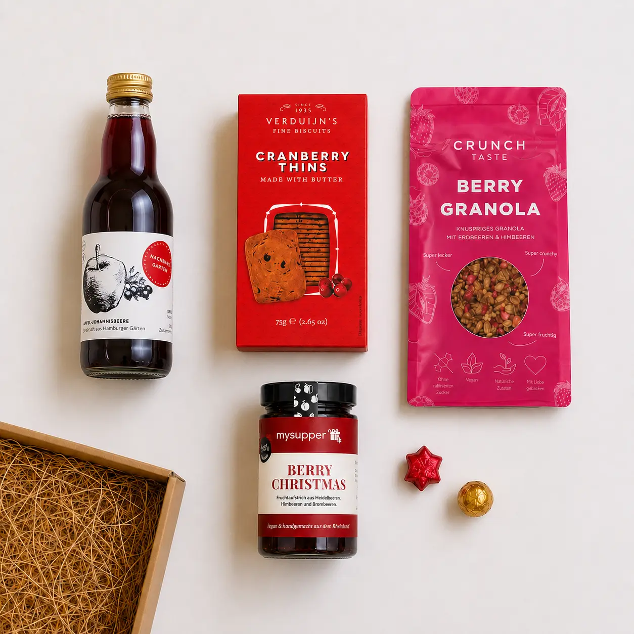 Inhalt der Geschenkbox Beerenstarke Weihnachten von mysupper mit Apfel-Johannisbeer-Saft, Cranberry-Crackern, veganem Beeren-Granola und Fruchtaufstrich